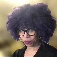 a woman with glasses and an afro looks at the camera