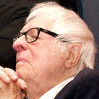 a man with a suit, glasses, and grey hair 